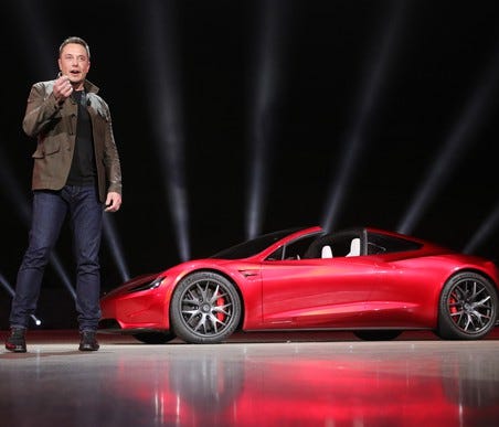 Elon Musk standing in front of the new Tesla Roadster