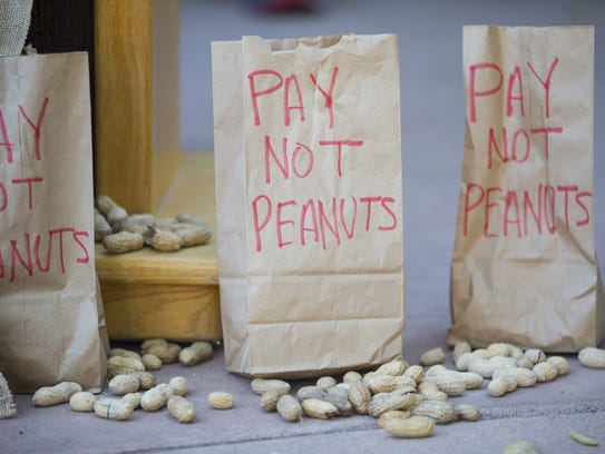 Bags titled "Pay not peanuts" sit underneath the podium