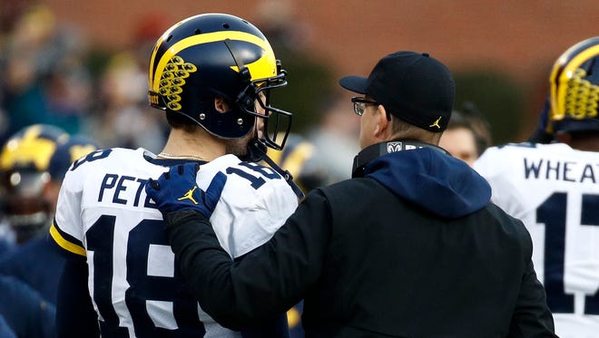 Michigan head coach Jim Harbaugh speaks with quarterback Brandon Peters in the first half.