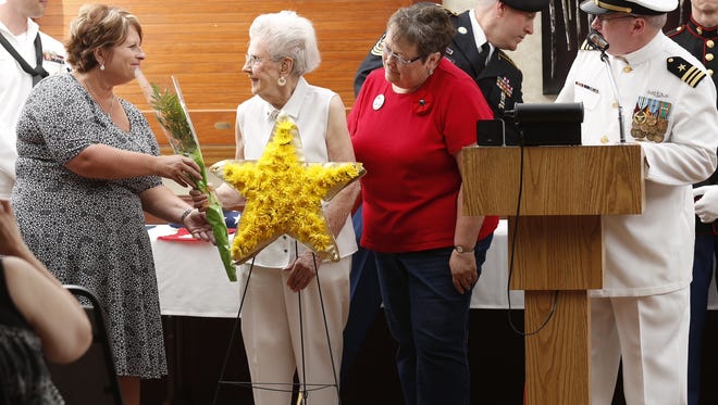 Sheyl Gellings, left, presented a floral arrangement to Doris Kosloske, who lost a son in Vietnam, as Sandy Smith and Ron Roen look on at a Flag Day ceremony Tuesday evening.