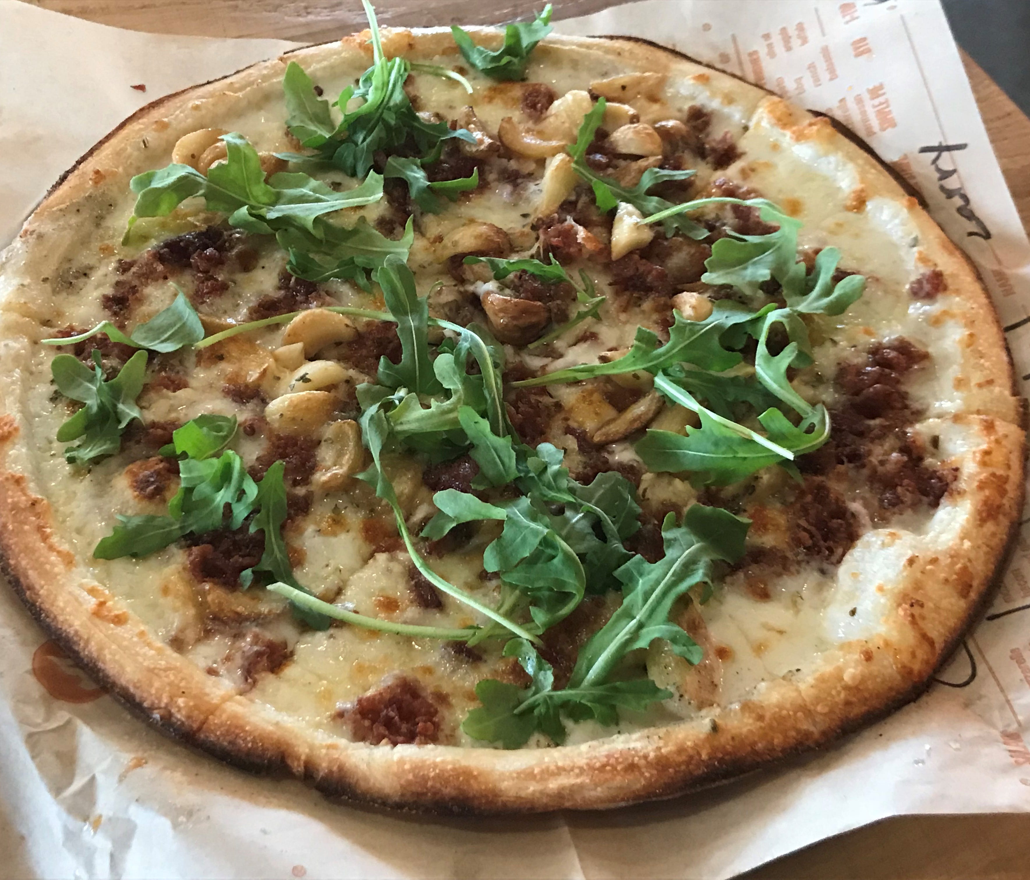 The signature White Top pizza has the option of adding roasted garlic cloves. It features a white cream sauce, mozzarella, Applewood bacon, oregano and baby arugula. All the signature and build your own (BYO) pies at Blaze are customizable with unlim