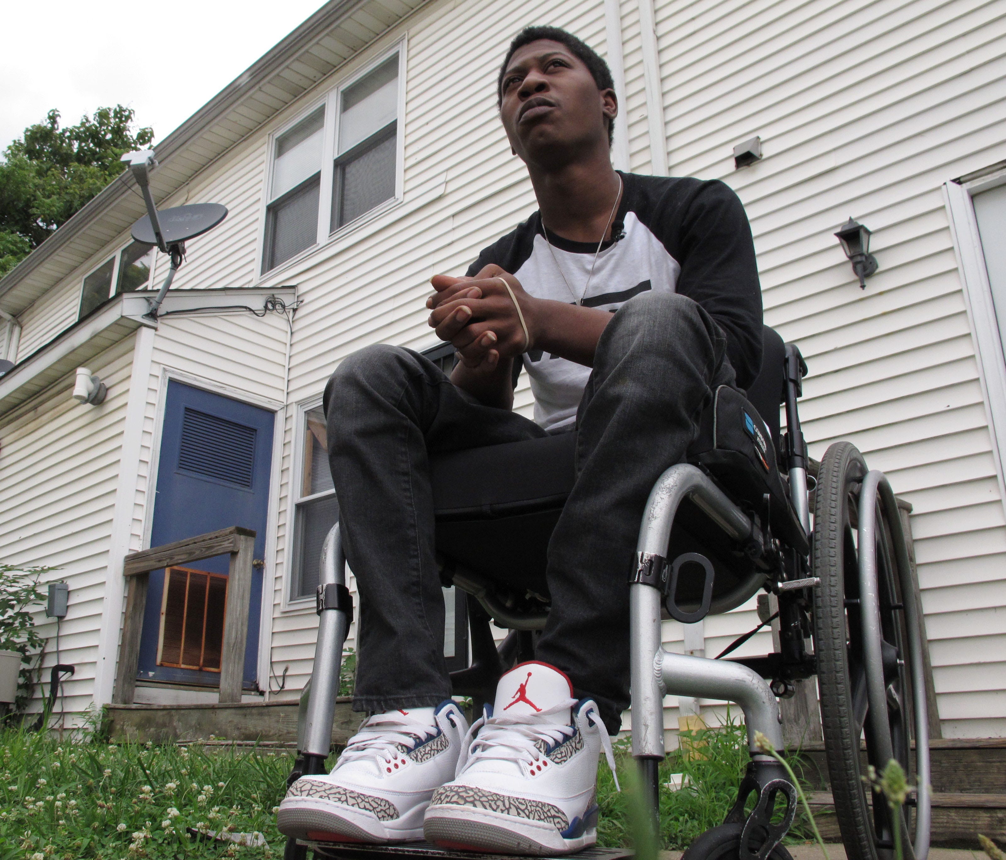 Rayquan Briscoe sits outside his home in Wilmington, Del. July 25, 2017. Two years ago, when he was 17, Briscoe was hit in the back by a stray bullet, leaving him paralyzed from the waist down.