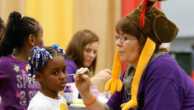 Emoni Burns, of North Avondale has a her face painted by Jana Smith of Crossroads Church during Give Back Cincinnati’s Fall Feast at Duke Energy Convention Center in 2015. This is the 14th year where those in need could get a free Thanksgiving Day meal, along with health screening, coats, hair cuts and more