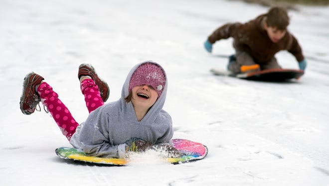 Nine-year-old Mattie Monteleone and her seven-year-old brother Bennett sled down Clement Drive after being released from school Wednesday morning following a brief period of snowfall. 