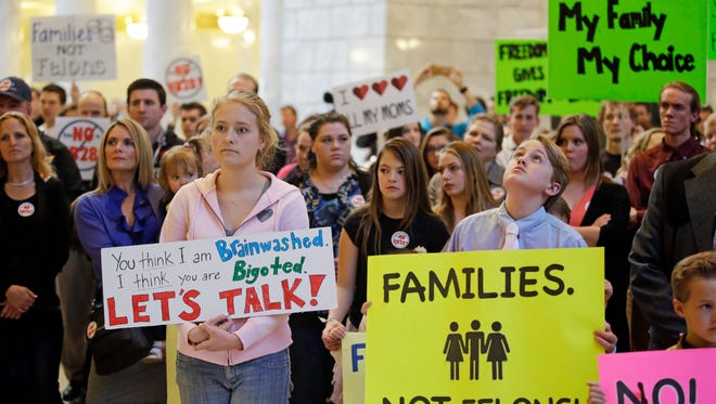 Polygamy advocate Hannah Willams, left, joins others gathering at the Utah State Capitol to protest a lawmaker's proposal that would make polygamy a felony crime again Monday, March 7, 2016, in Salt Lake City. About 150 pro-polygamy activists and their children protested, holding signs and giving speeches criticizing the proposed law.