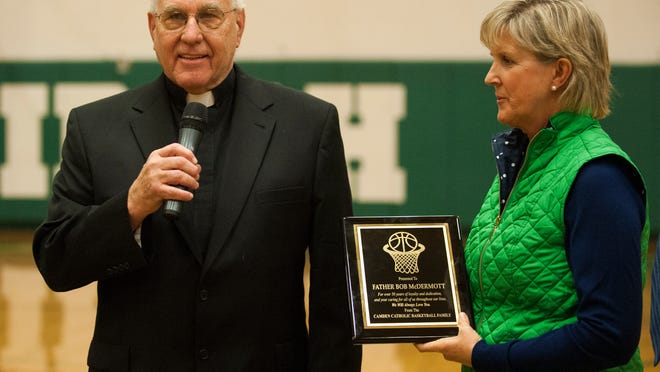 Mary Whipkey presents Monsignor Bob McDermott with a plaque to commemorate his service to the Camden Catholic basketball program.