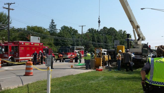 Work crews and firefighters work to recover body parts from a sewer line in Sterling Heights, Mich., in August 2012.