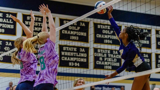 Hickman's Jerica Jackson (4) spikes the ball against a pair of Helias blockers Thursday night at Helias High School in Jefferson City.