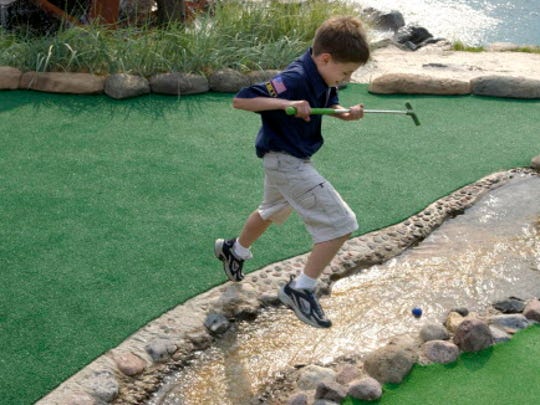 Alexei Ward jumps over the water hazard where his ball landed while playing miniature golf at Moorland Golf Center.