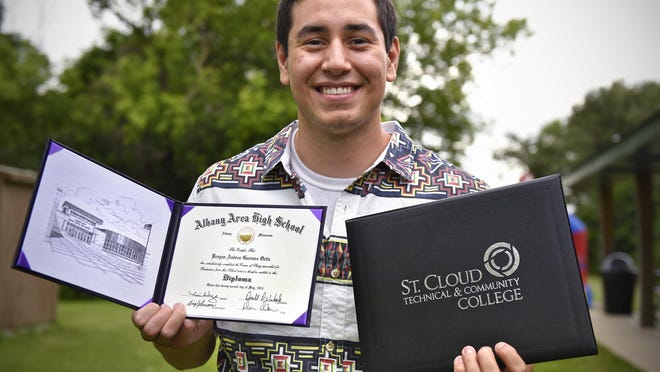 Brayan Guevara holds his degree from St. Cloud Technical & Community College and diploma from Albany High School during his graduation party Friday at North Park in Albany.