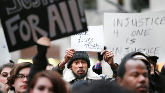 Courtland Gaines of Indianapolis holds a sign as he and others observed a 4 1/2-minute moment of silence to mark the 4 1/2 hours that Michael Brown's body remained on a Ferguson street before it was removed on Aug. 9.