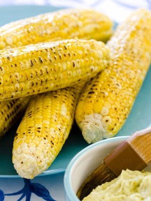This undated photo provided by America's Test Kitchen in May 2018 shows grilled corn on the cob, but the grill can be used for baking as well as grilling.