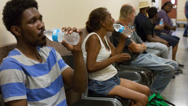 Maceo Jackson, 23, and Maria Moreno, 58, drink water that's handed to them as they wait in line to work with the Homeless ID Project on June 6, 2018, in Phoenix, Arizona.