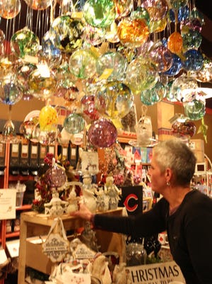 College Hill Coffee Company owner Tina Stoeberl adjusts items displayed in the gift shop within the shop.