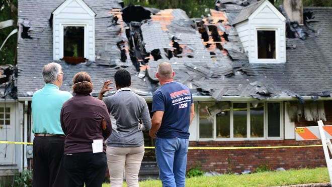 Second from right, Betty Adams, the home owner stand in front of her burned-out home in Hawthorne. Two firefighters were treated for minor injuries.