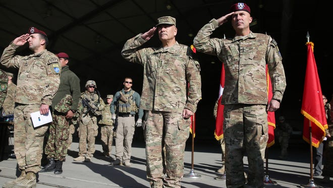 International Security Assistance Force Joint Command (IJC), Lieutenant General Joseph Anderson, right, and  commander of International Security Assistance Force, General John F. Campbell, center, salute during a flag-lowering ceremony in Kabul, Afghanistan, Monday, Dec. 8, 2014. The U.S. and NATO ceremonially ended their combat mission in Afghanistan on Monday, 13 years after the Sept. 11 terror attacks sparked their invasion of the country to topple the Taliban-led government. From Jan. 1, the coalition will maintain a force of 13,000 troops in Afghanistan, down from a peak around 140,000 in 2011. There are around 15,000 troops now in the country.(AP Photo/Massoud Hossaini)