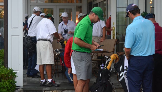 Golfers sign and hand in scorecards Monday evening after play in a sectional qualifier for the U.S. Amateur was suspended a second time due to storms in the vicinity of Trump National-Westchester.