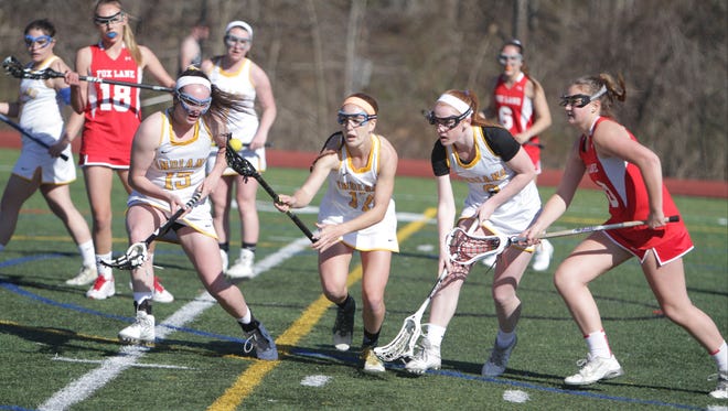 Mahopac's Ali Korin (center) scoops up a ground ball with teammates Katie Semenetz (15) and Alyssa Kirby (right) looking on, during a Section 1 girls lacrosse game between Mahopac and Fox Lane at Mahopac High School on Friday, April 15th, 2016. Mahopac won in overtime 9-8.