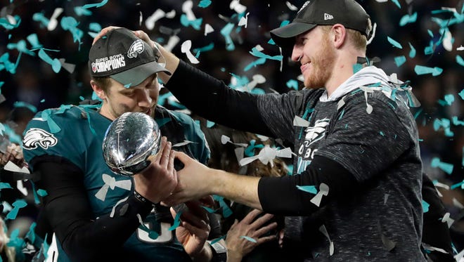 Philadelphia Eagles quarterback Carson Wentz, right, hands the Vincent Lombardi trophy to Nick Foles after winning the NFL Super Bowl 52 football game against the New England Patriots in Minneapolis. The Eagles won 41-33.