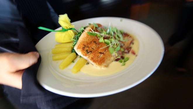 A plate of pan-fried Lake Superior Whitefish with lemon caper butter, wilted spinach, and root vegetables is delivered to a table at Spencer's Restaurant in Palm Springs, one of 70-plus Coachella Valley participants in Dining Out for Life on April 27.