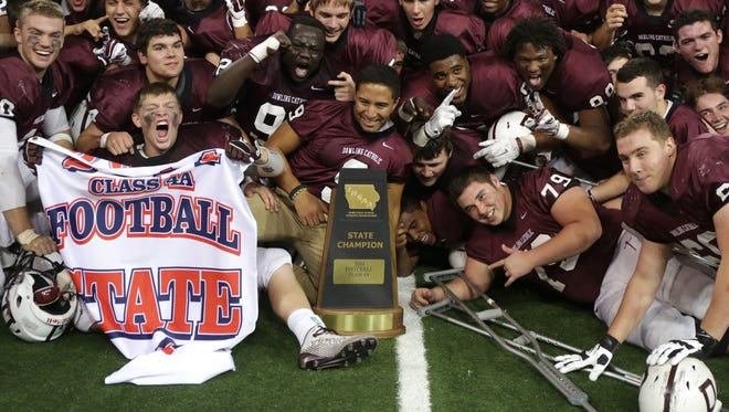 Members of the Dowling Catholic football team celebrate with their trophy after a win over Cedar Rapids Washington in the Iowa Class 4A state football championship game on Friday, Nov. 21, 2014, at the UNI-Dome in Cedar Falls, Iowa.