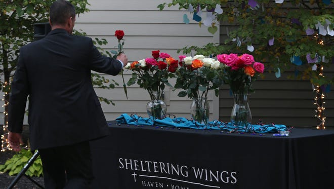 People place flowers in memory of domestic violence victims at Sheltering Wings' annual vigil in Danville on Tuesday, September 30, 2014.