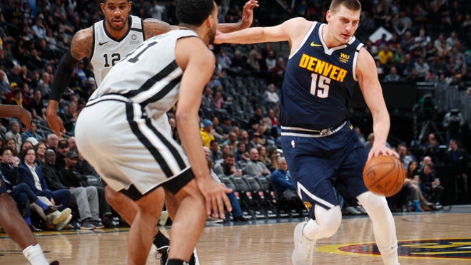 Denver Nuggets center Nikola Jokic, right, drives past San Antonio Spurs forward LaMarcus Aldridge, back left, as center Trey Lyles, front left, waits in the paint to defend in the first half of an NBA basketball game Monday, Feb. 10, 2020, in Denver. (AP Photo/David Zalubowski)