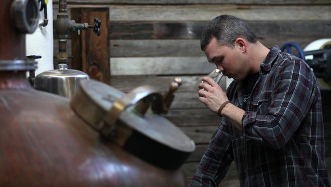 Drew Wescott, head distiller, at Iron Smoke Whiskey, checks the smell and taste of his whiskey at the new distillery that moved from Seneca Falls and opened in Fairport about a month ago.