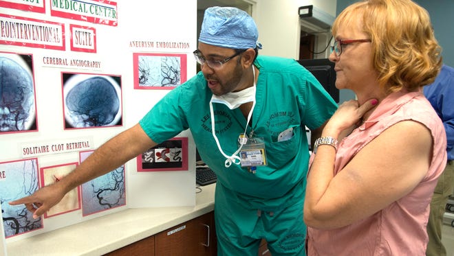 Earl Robinson , left, a radiologic technologist at Gulf Coast Medical Center shows former patient, Sharon Warwick of Cape Coral  the images of before and after the surgery she had recentlly to retrieve a blood clot in her brain. Warwick was treated by  Dr. Nasser Razack M.D. using the Siemens Artis Zee bi-plane imaging system. The system, recently acquired by Gulf Coast, expands its capabilities to treat intracranian aneuyrysms, vascular malformations and stroke.