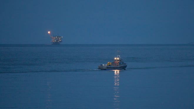 An oil platform sits in the distance as a boat is used to try to clean up an oil spill before dawn off Refugio State Beach on May 20, 2015 north of Goleta, California.