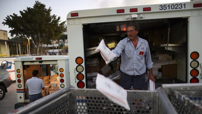 Jay Oceguera, a U.S. Postal Service mail handler, unloads a mail truck at a Processing and Distribution Center on the busiest mailing day of the year for the U.S. Postal Service on December 19, 2016 in Miami, Florida.