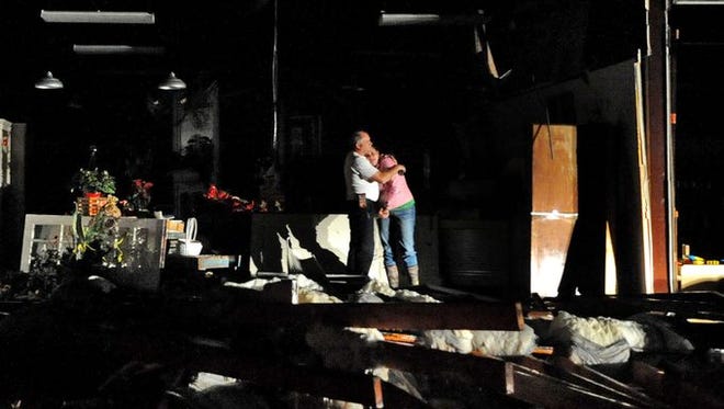 Jeff and Melissa McKenzie embrace in the ruins of their florist and gift shop store in Columbia, Miss., after a tornado ripped through the city Tuesday, Dec. 23, 2014. According to Marion County Emergency Management the tornado touched down around 2:30 p.m. Tuesday.