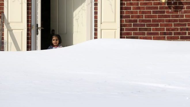 Two-year-old Gianna Patel peers over a snow bank in the front yard of her family's Franklin Township home, Sunday, January 24, 2016.