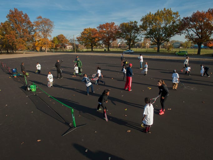 Children learn to play tennis during a ceremony for