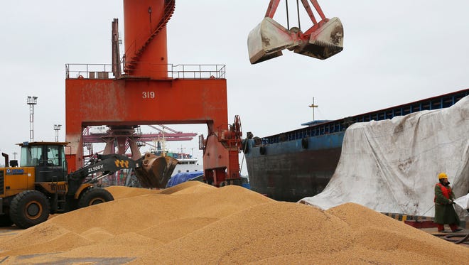 In this Wednesday, April 4, 2018 photo, workers load soybeans imported from Brazil at a port in Nantong in east China's Jiangsu province.