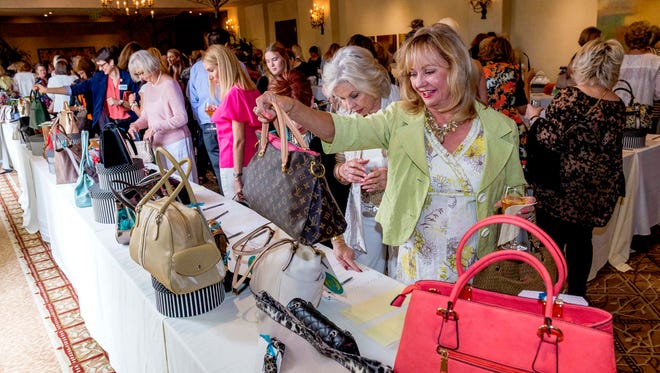 Gayle Hodges, right, admires a silent auction offering at the Old Bags Luncheon, a benefit for CancerPartners, in March 2018.