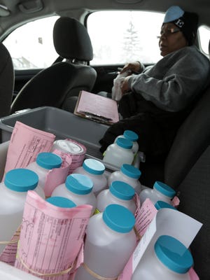 Flint resident Karen Rawls sits with water samples collected from Flint residents in the sentinel site program by the Department of Environmental Quality sit in a car as DEQ representatives and Flint ambassadors go house to house collecting the samples from Flint residents on Wednesday, March 2, 2016.