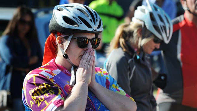 A rider clasps her hands to her face as the names of the victims are read at the beginning of the ride.
