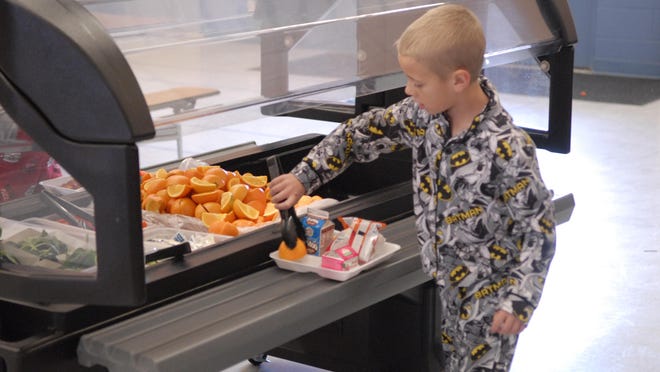 One Fernley Elementary School student, decked out in his Batman nightwear for Pajama Day, selects an orange as part of his fruit option at lunchtime Friday.