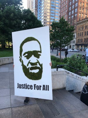 A protestor carries a poster featuring a picture of George Floyd on May 31, 2020. Floyd, a 46-year-old black man, was killed while in police custody after allegedly passing a counterfeit $20 bill at a convenience store.