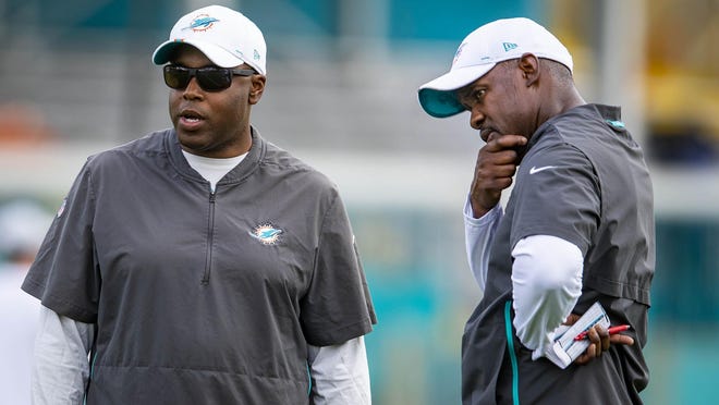 Dolphins general manager Chris Grier (left) and coach Brian Flores during workouts last summer.