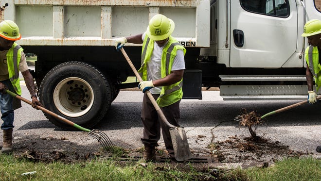 August 29, 2017 - From left, Kermichael Futrell, Jeffery Sanders and Marico Craft, a City of Memphis public works crew, clean out a storm drain on North Willett Tuesday afternoon in anticipation of rain from the Hurricane Harvey storm system.
