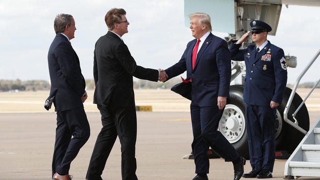 President Donald Trump greets Lt. Governor Dan Patrick and Attorney General Ken Paxton, far left, at Austin Bergstrom International Airport on Nov. 20, 2019 before his visit to the Apple campus.