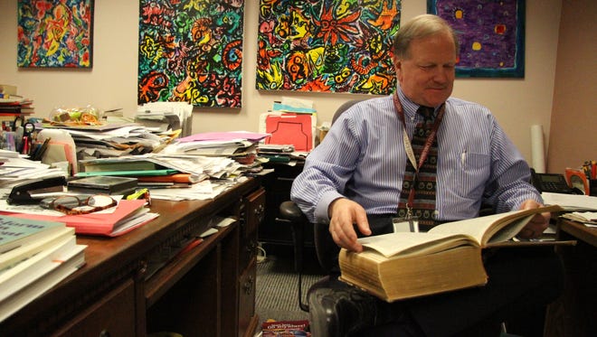 Mike Cleary used a dictionary to look up the word "bodhrán," a type of Irish drum he plans on learning upon retirement, in his office.