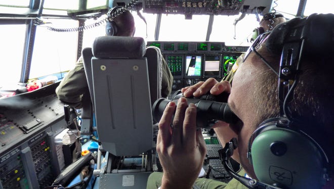 In this image released by the U.S. Coast Guard, Petty Officer 1st Class Mike Crosby, right, scans the surface of the Atlantic Ocean through his binoculars while in the cockpit of a Coast Guard HC-130J on July 28, 2015, while searching for Florida teens Perry Cohen and Austin Stephanos.