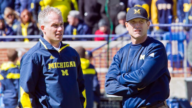 Michigan defensive coordinator D.J. Durkin, left, and head coach Jim Harbaugh, right, watch players warmup before the NCAA college football team's spring game in Ann Arbor, Mich., Saturday, April 4, 2015.