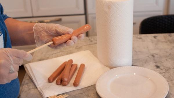 Begin by placing a wooden skewer through each hot dog.