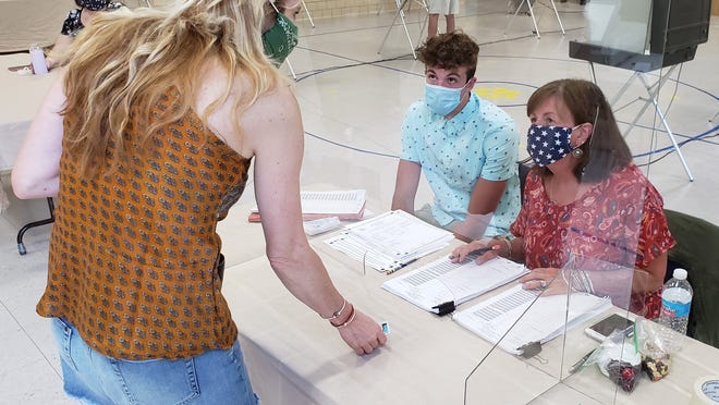 Nancy Davis checks in with James Rooney and Marcia McChesney before voting Saturday at Cold Spring Elementary School.