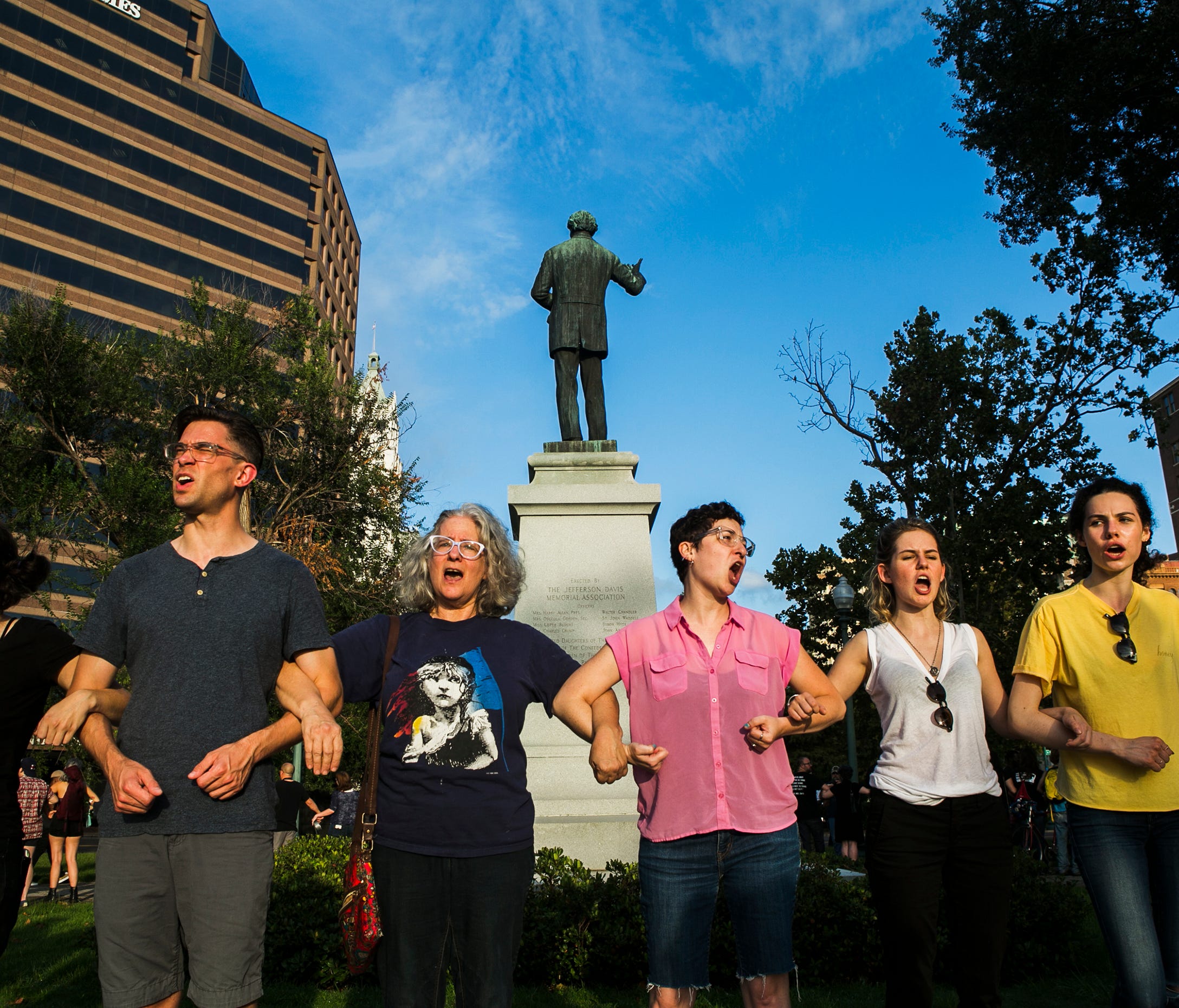 Protesters link arms as they surround the Jefferson Davis Confederate statue at Memphis Park on Tuesday. The action comes days following the death of Heather Heyer following the 