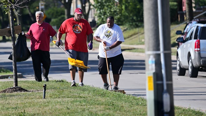 Residents and others who came to Milwaukee's Sherman Park neighborhood on Aug. 14, 2016, prayed for peace then got out trash bags to clean up the mess of rioting the night before.